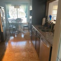 A kitchen with a sink , refrigerator , dishwasher , table and chairs.