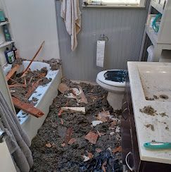 A bathroom with a bathtub , toilet , sink and a lot of dirt on the floor.