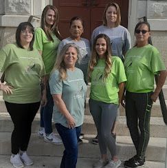 A group of women in green shirts are posing for a picture.