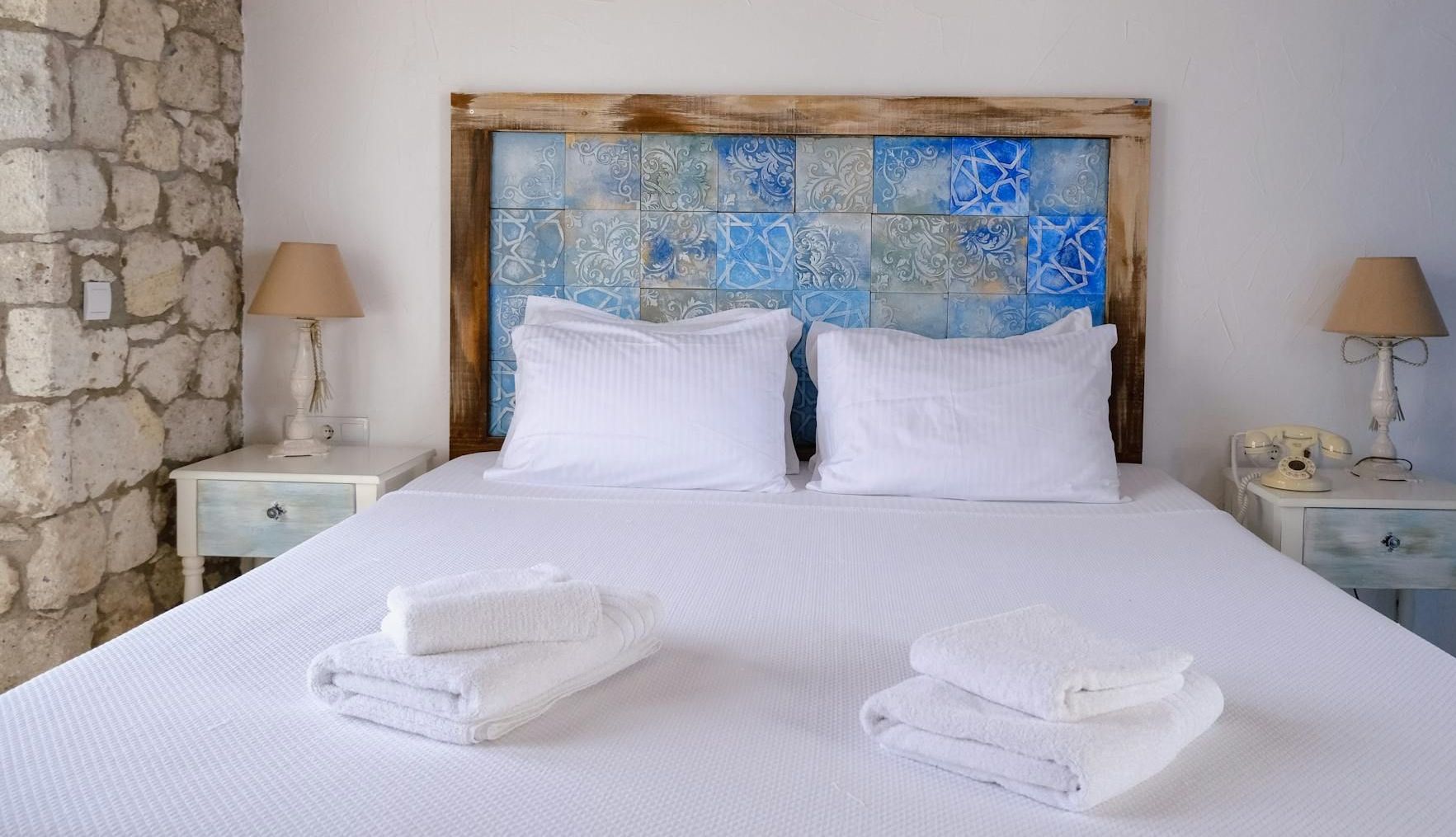 A bed with white sheets and pillows in a bedroom with a wooden headboard.