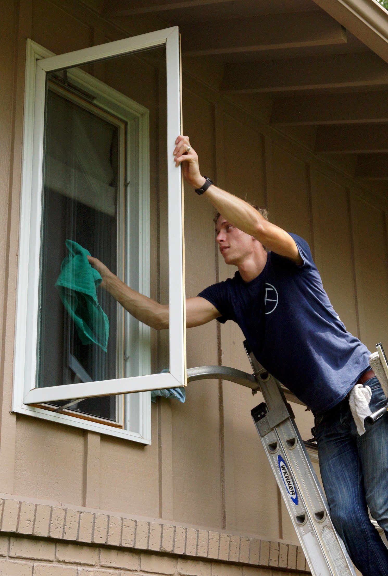 a man is standing on a ladder cleaning a window .