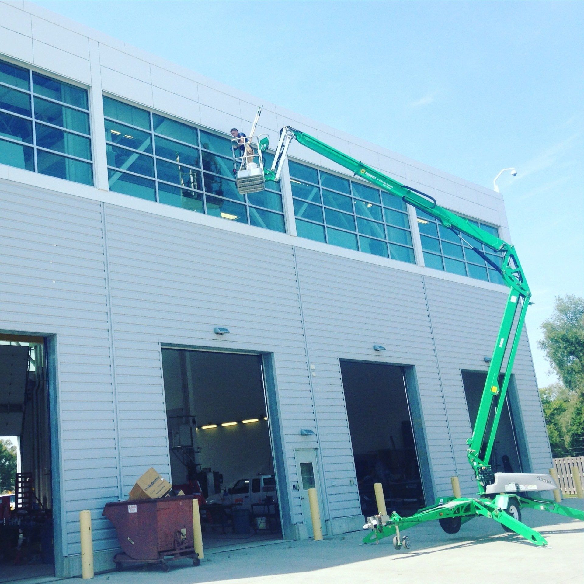 a green crane is parked in front of a building