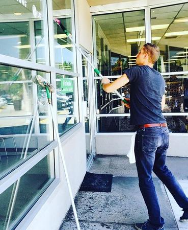 a man is cleaning the windows of a building with a mop .