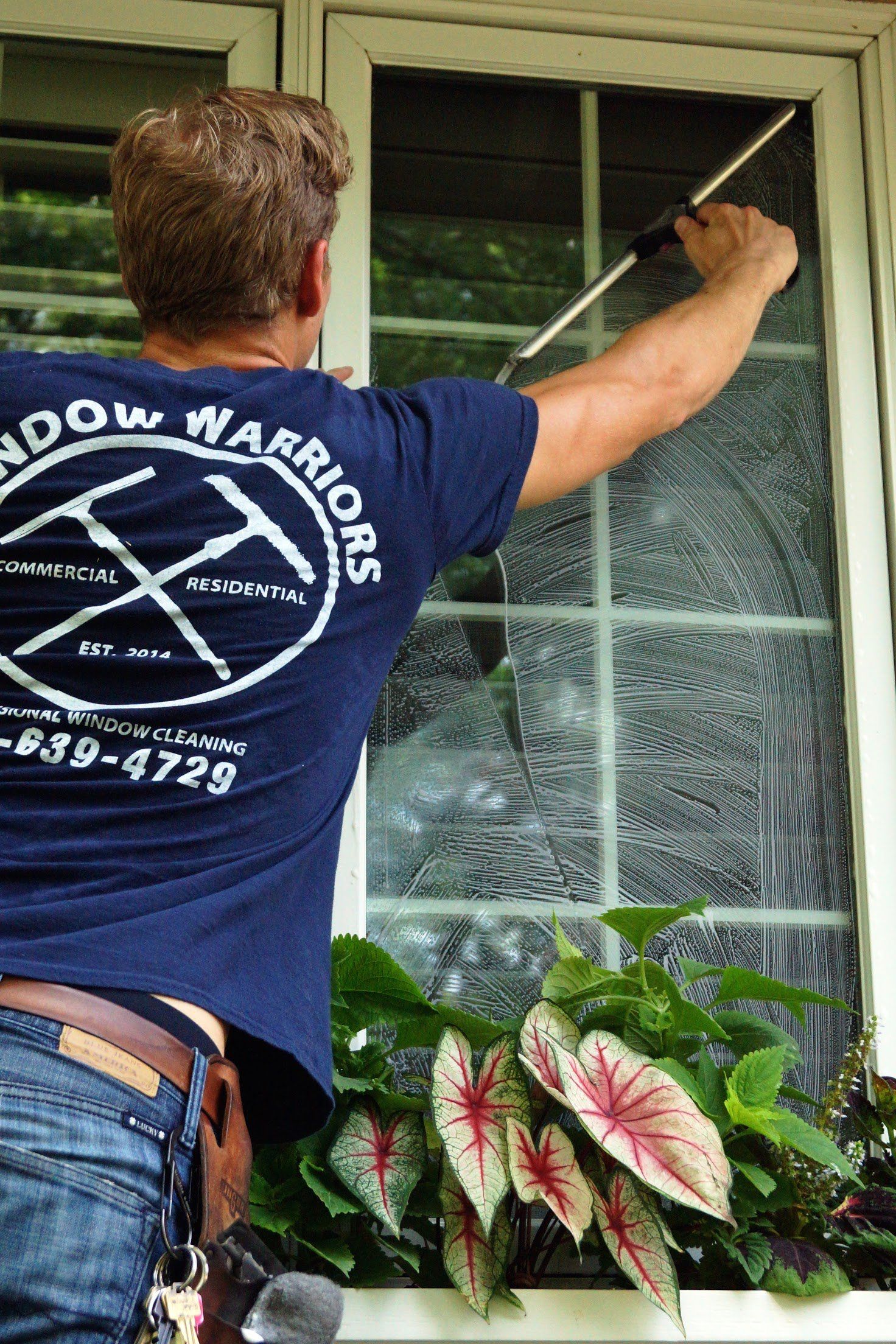 a man in a blue shirt is cleaning a window with a brush .