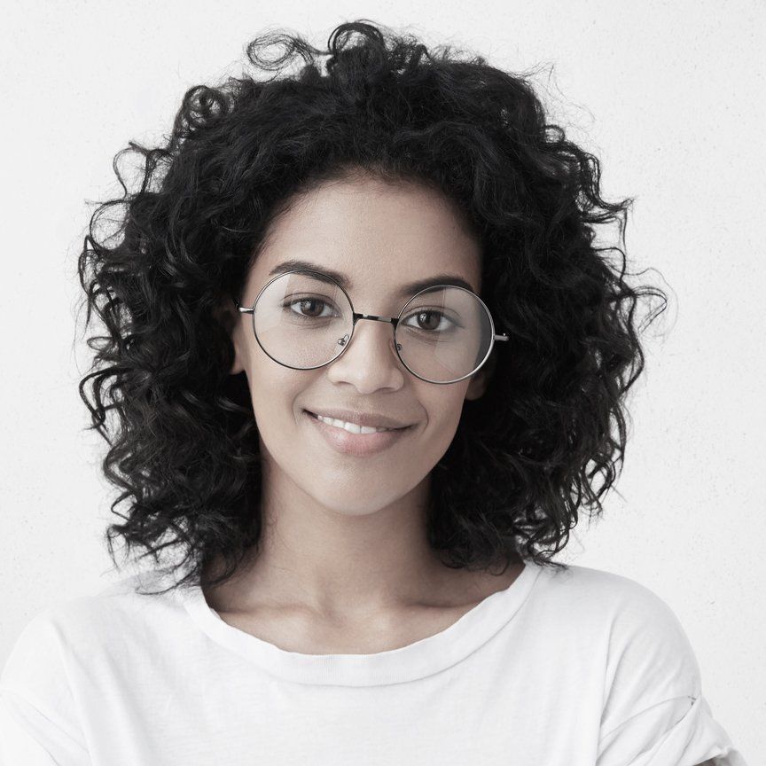 a woman with curly hair wearing glasses and a white shirt