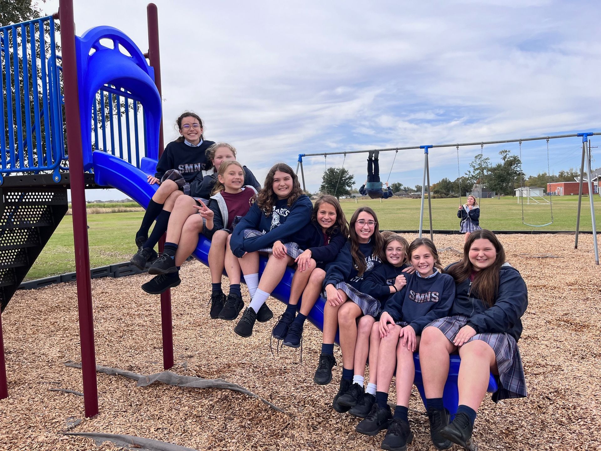 a group of female students sitting on a slide