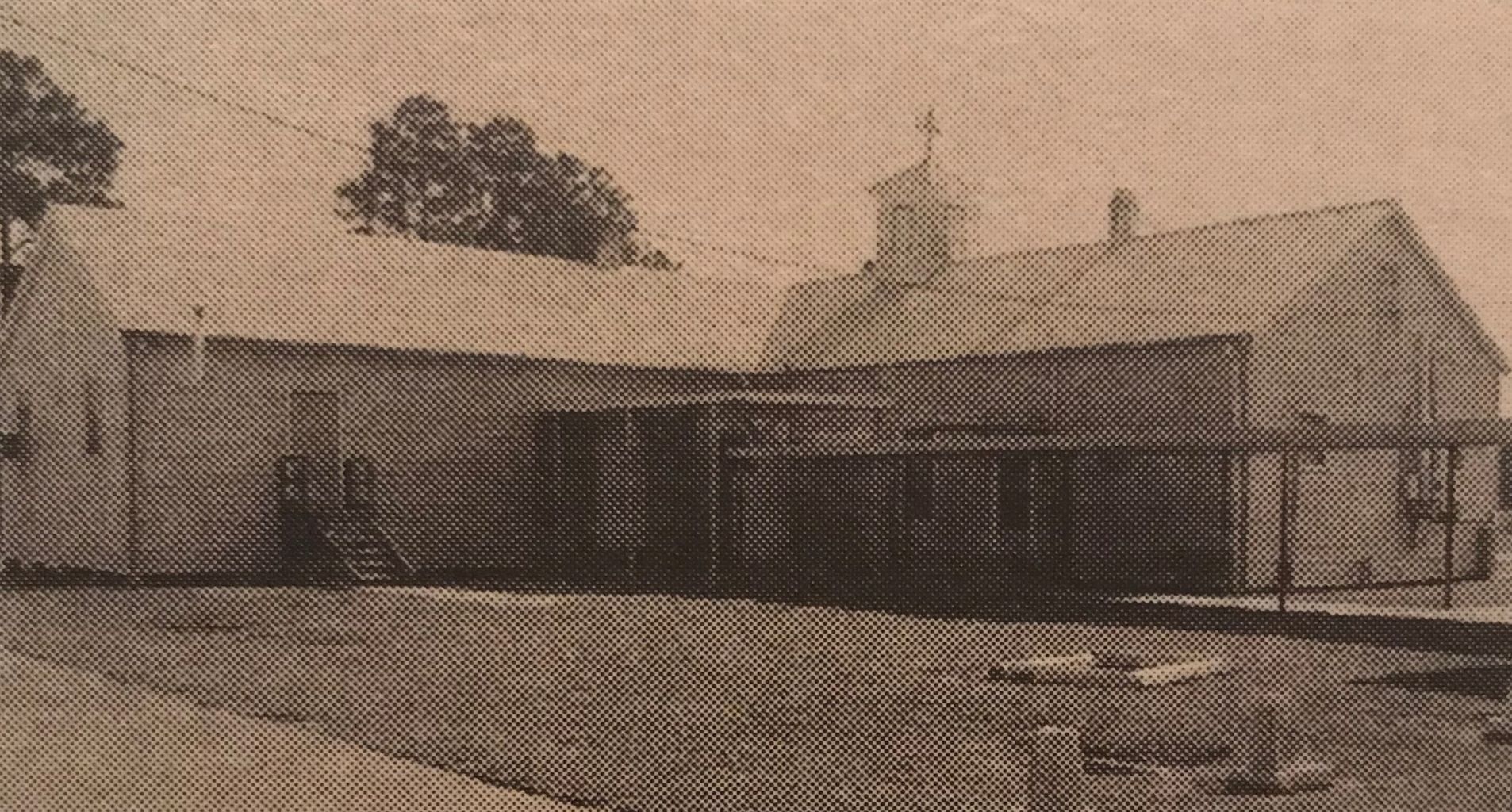 A black and white photo of a house with a cross on the roof