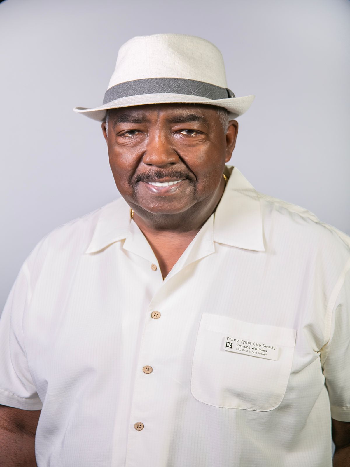 A man wearing a black shirt and a white hat smiles for the camera