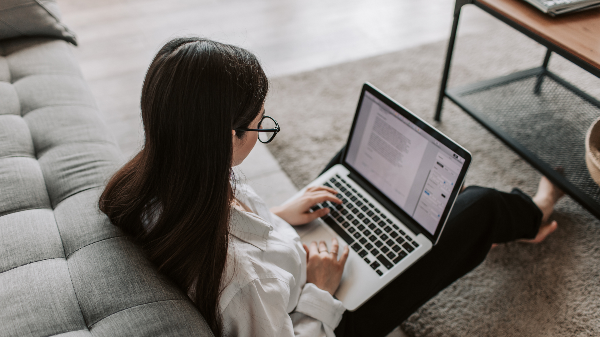 A woman is sitting at a desk using a laptop computer.