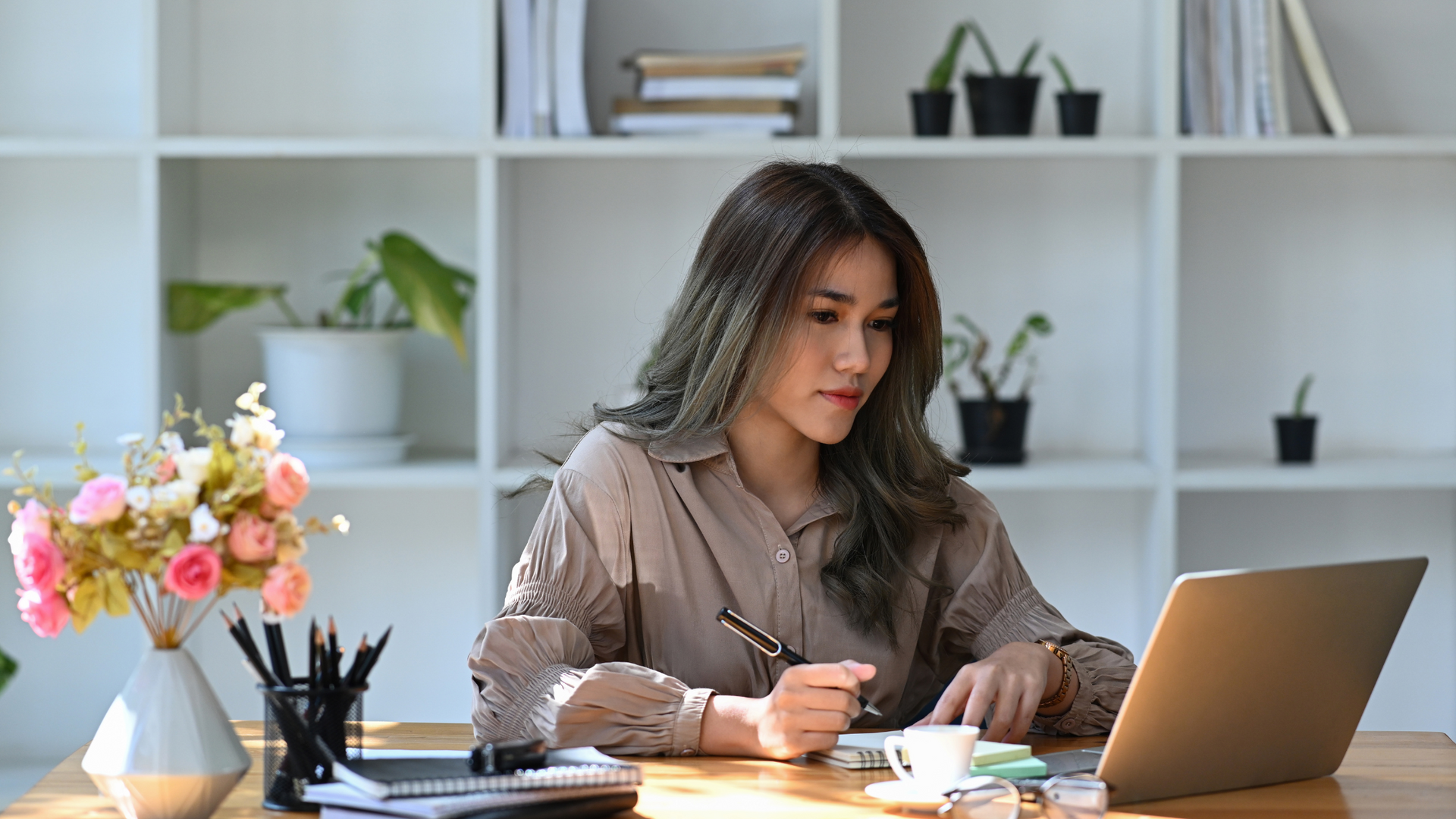 A woman is sitting at a desk using a laptop computer.