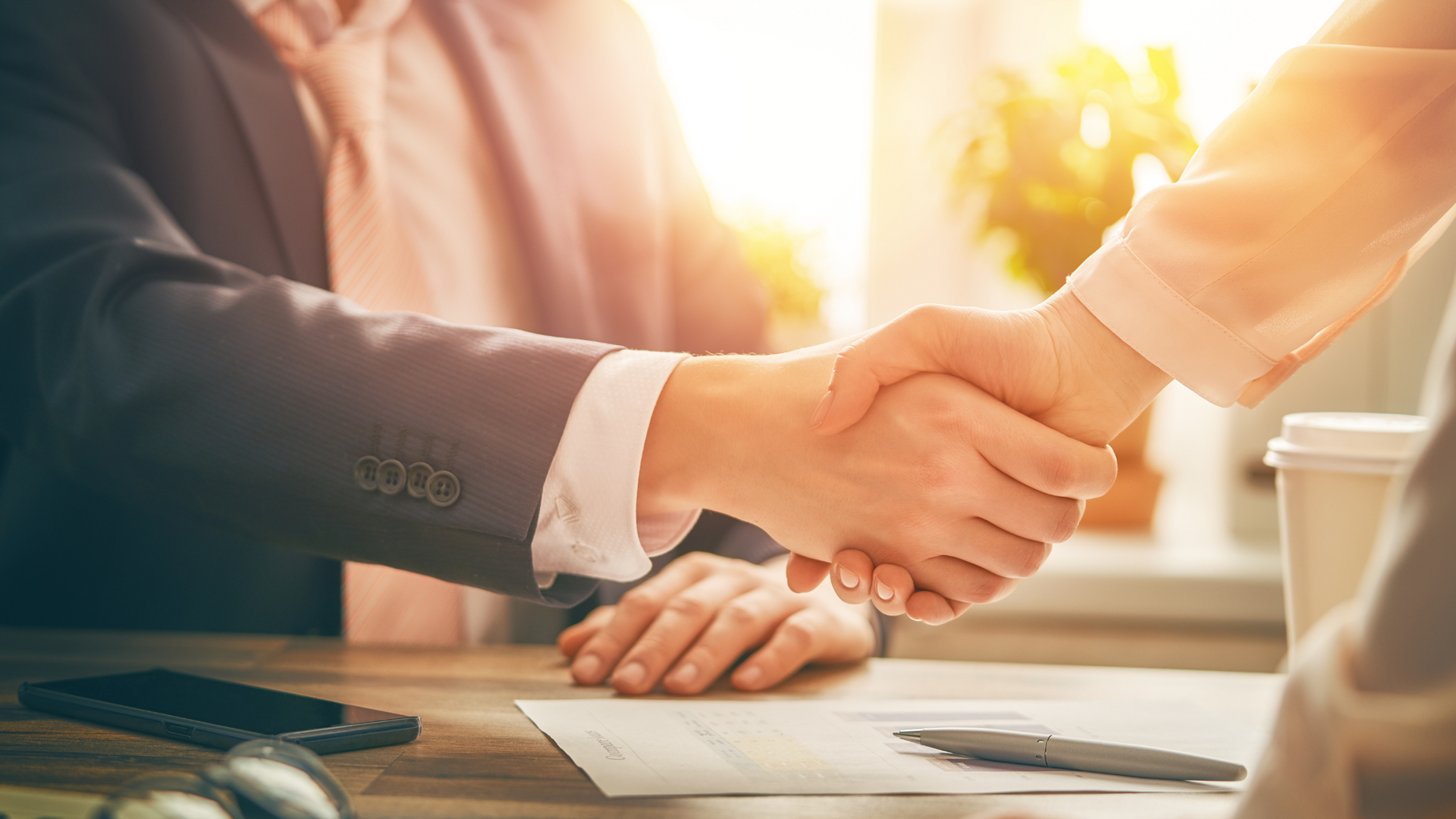 A man and a woman are shaking hands over a table.