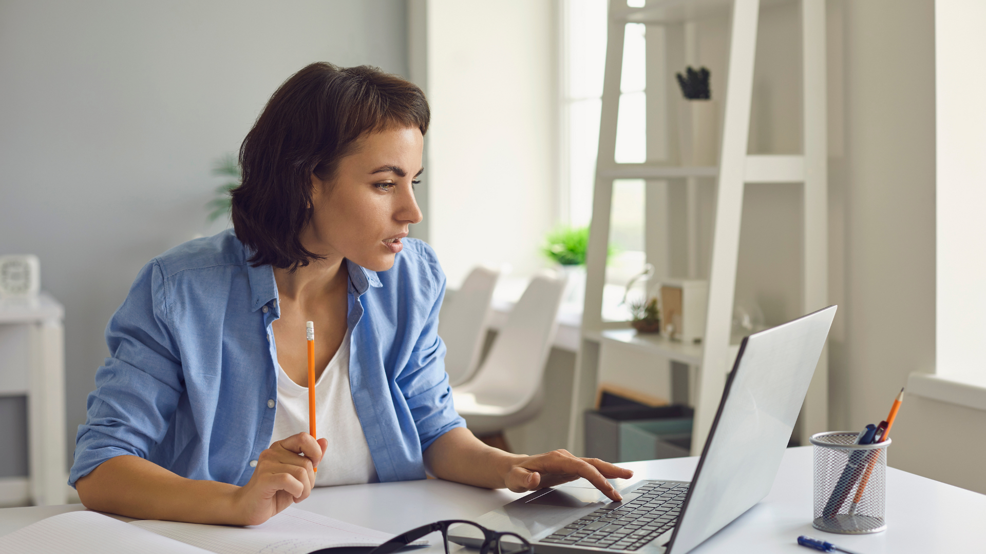 A woman is sitting at a desk using a laptop computer.