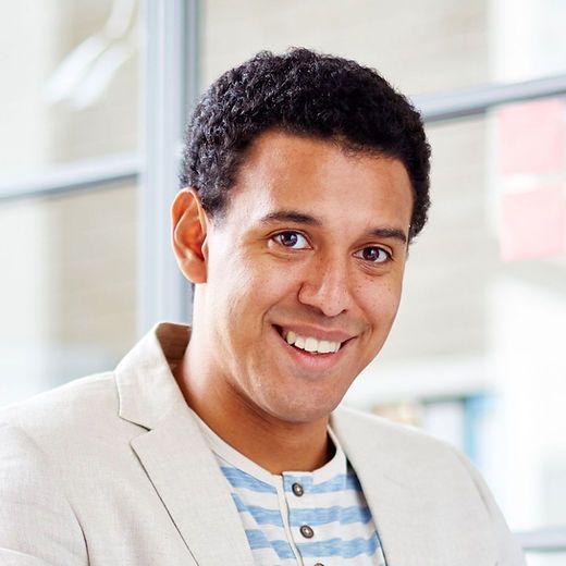 A man in a suit and striped shirt smiles for the camera