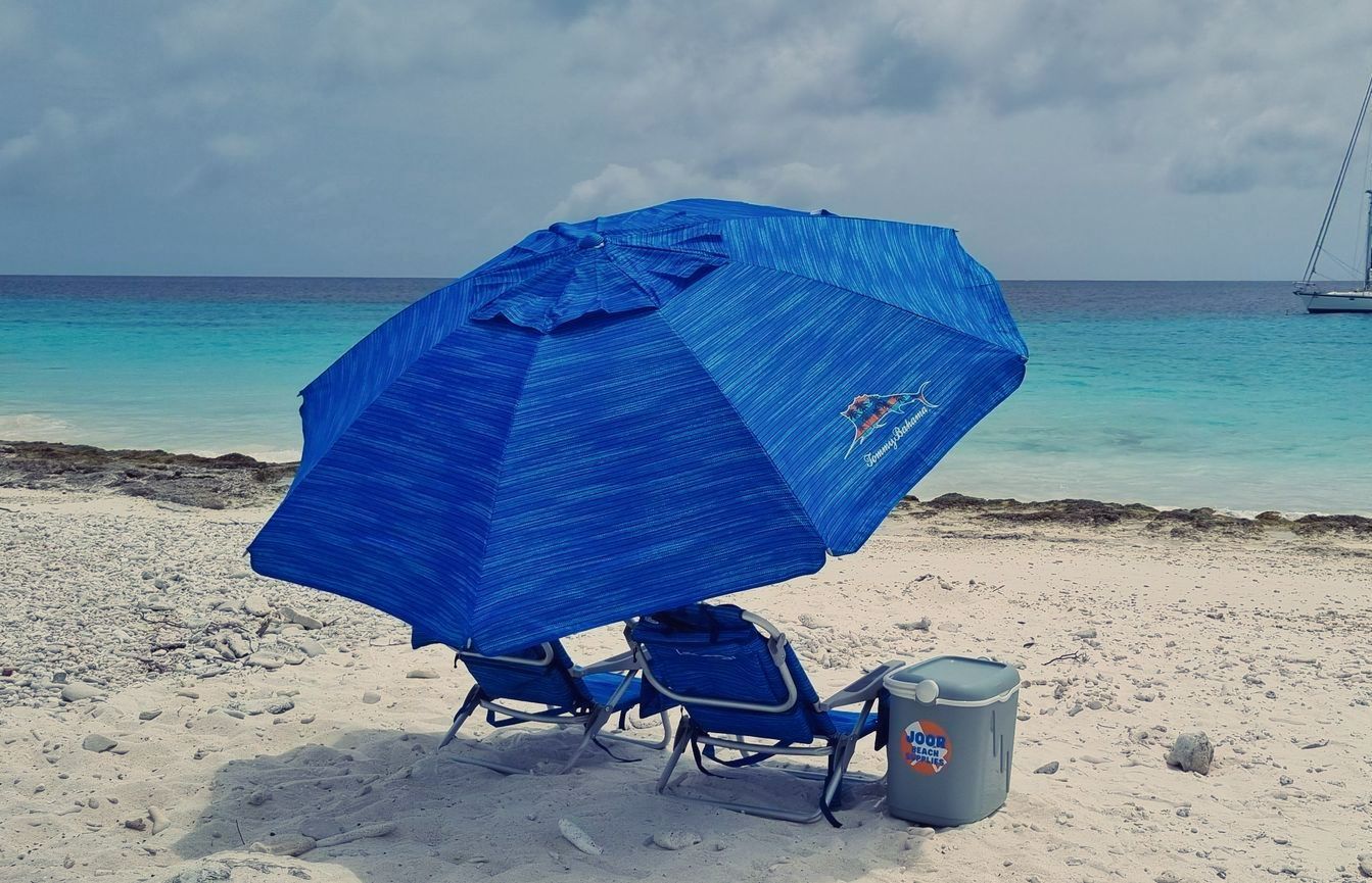 Two beach chairs, a beach umbrella and a cooler for rent for usage on the beaches of Bonaire