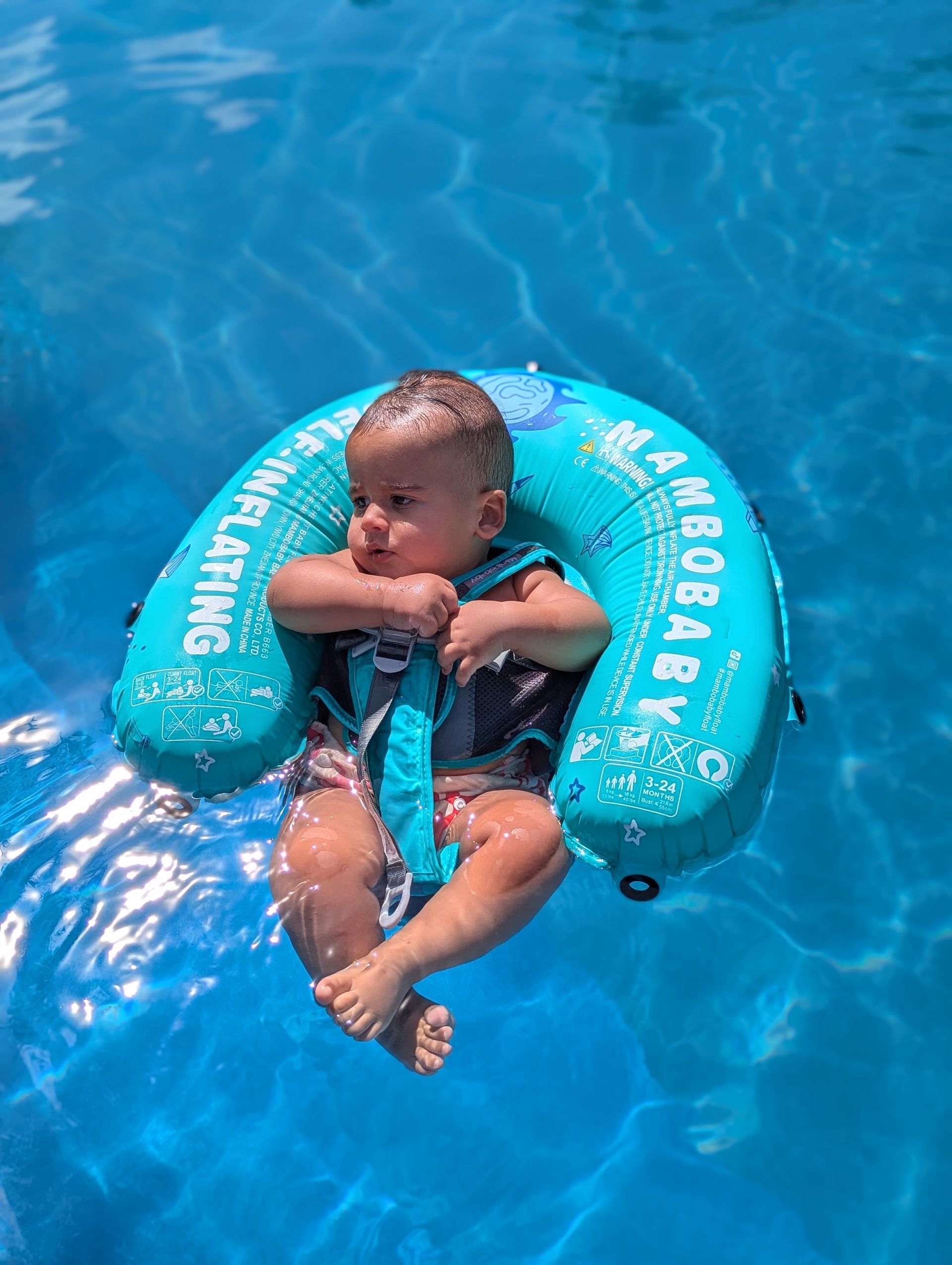 Een baby die veilig in een blauwe baby float zwemband dobbert in het heldere zeewater van Bonaire.