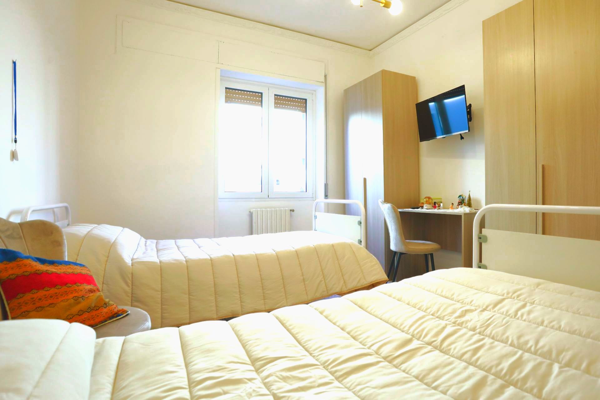 Una camera doppia con due letti, una finestra, una scrivania, una TV e un armadio.