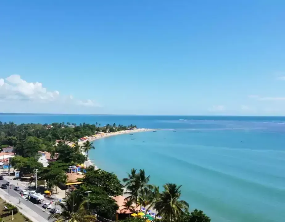 Uma vista aérea de uma praia com palmeiras e uma estrada que leva ao oceano Areia do Atlântico Hotel