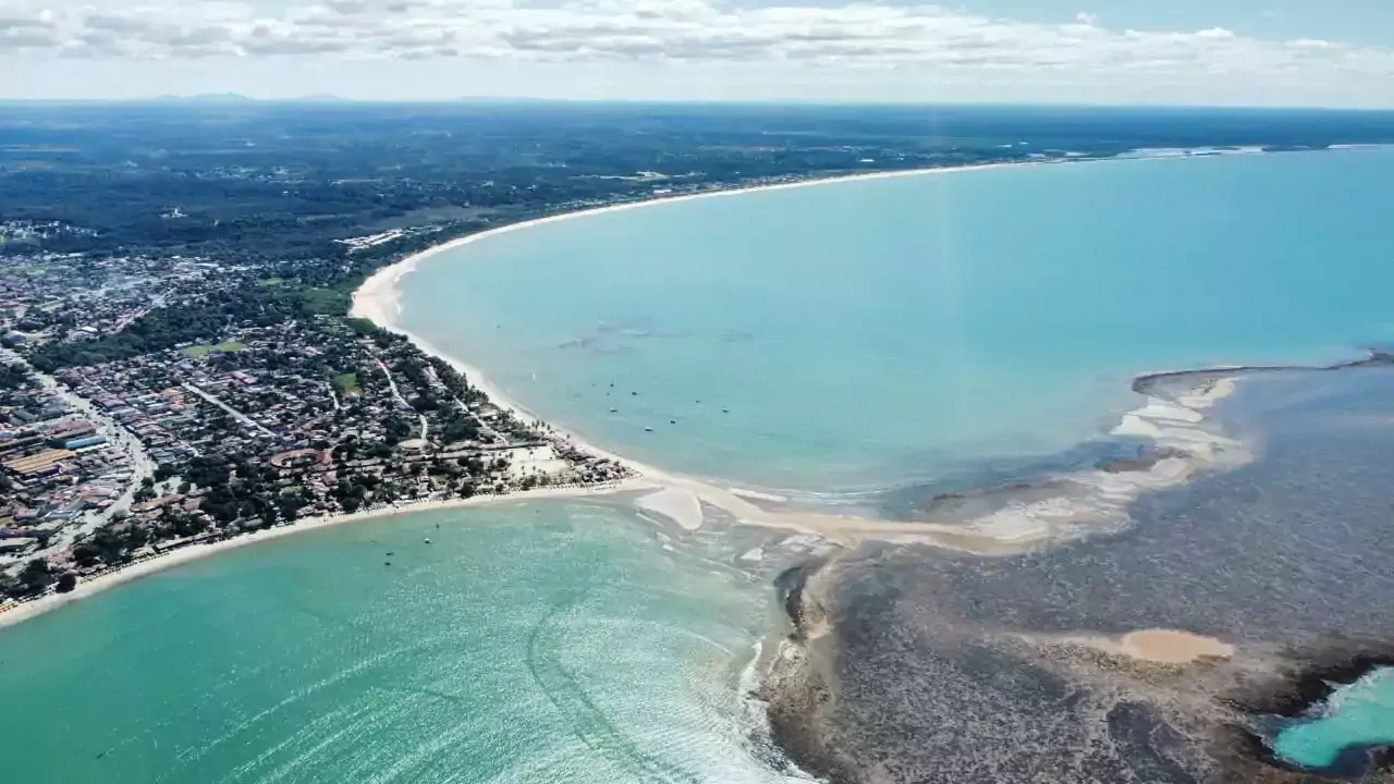 Uma vista aérea de um grande corpo de água com uma cidade ao fundo Areia do Atlântico Hotel