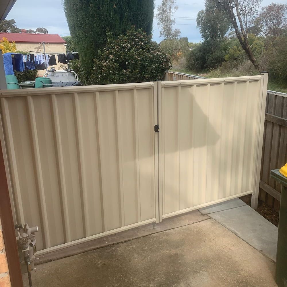 A White Fence With a Green Trash Can in Front of It — CLF Landscaping In Hawker, ACT
