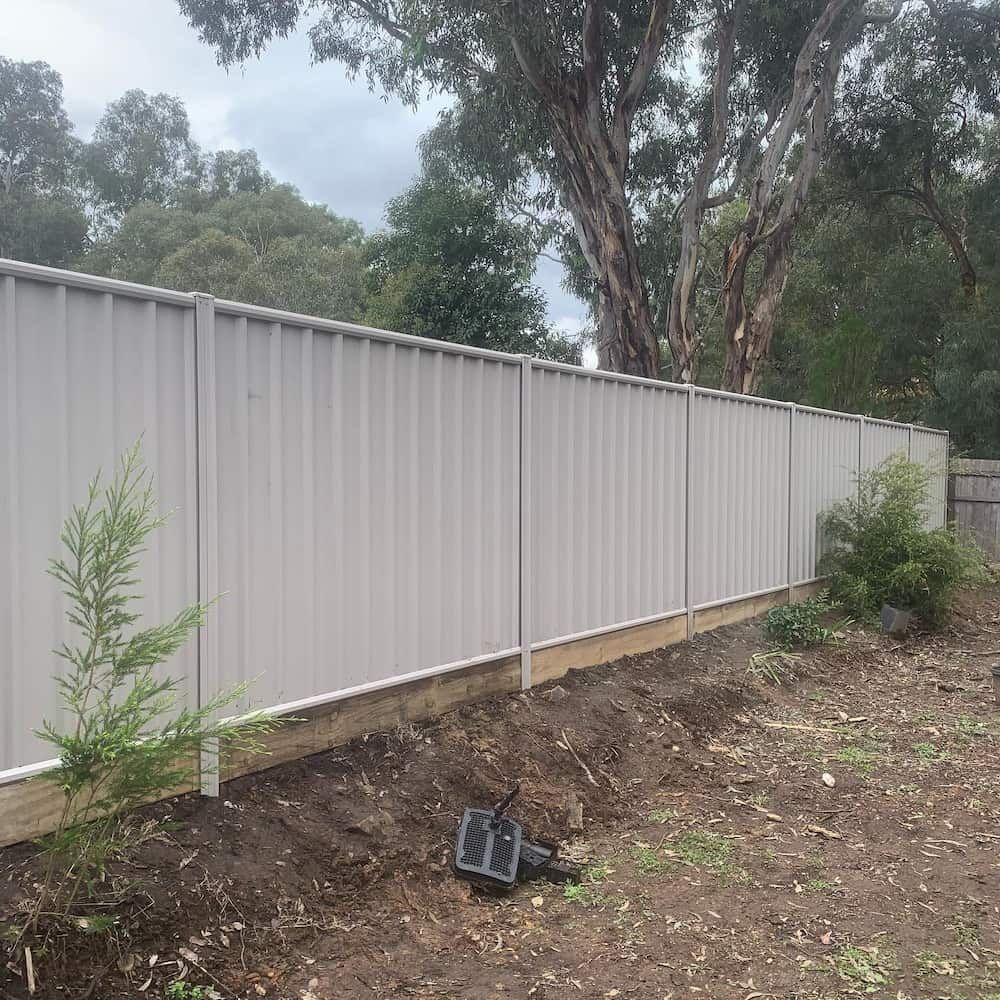 A White Fence Surrounds a Dirt Field With Trees in the Background — CLF Landscaping In Hawker, ACT