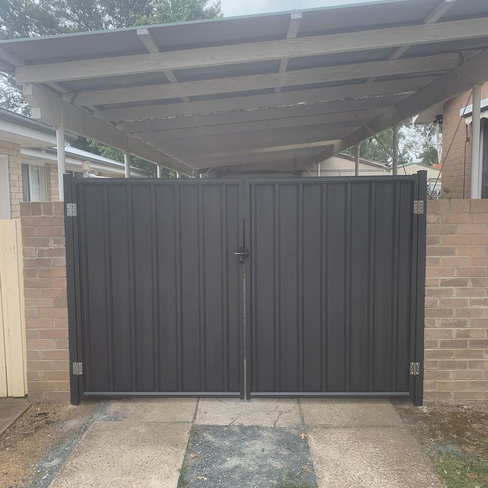 A Black Gate is in Front of a Brick Building — CLF Landscaping In Hawker, ACT