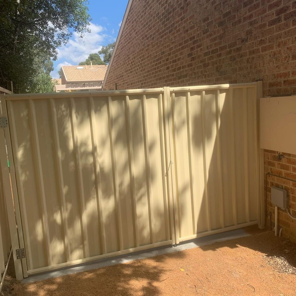 A White Gate is Sitting in Front of a Brick Building — CLF Landscaping In Hawker, ACT