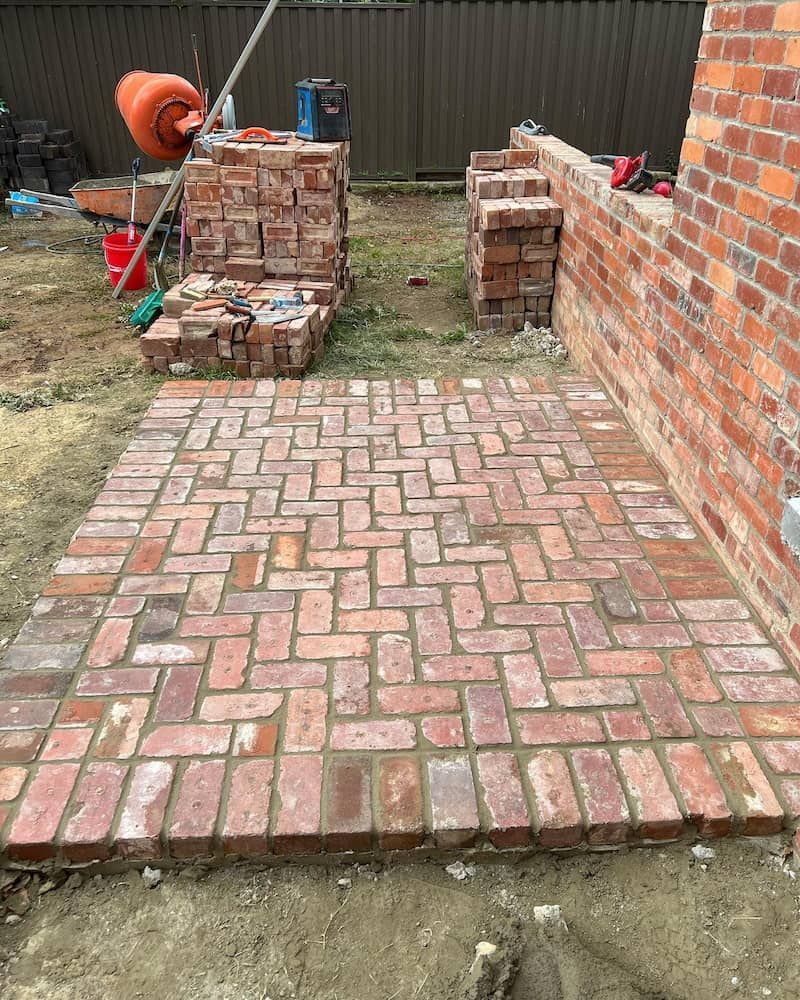 A Brick Walkway is Being Built in Front of a Brick Wall — CLF Landscaping In Hawker, ACT