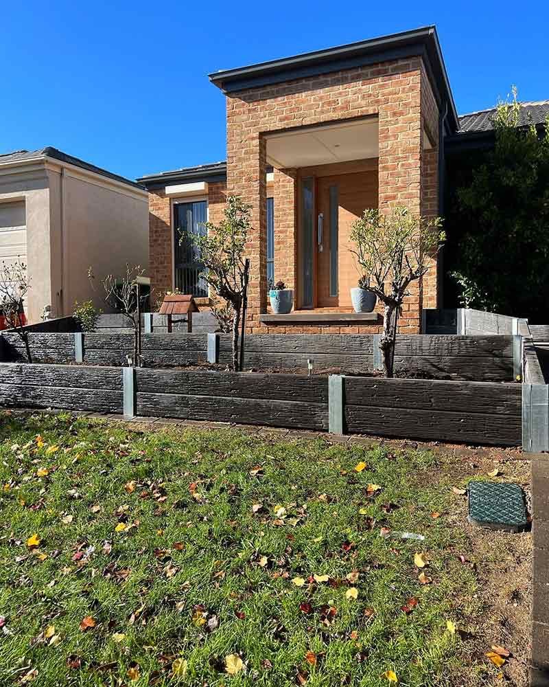 Brick House With Tiered, Weathered Wooden Planter Boxes in Front — CLF Landscapes in Queanbeyan, NSW