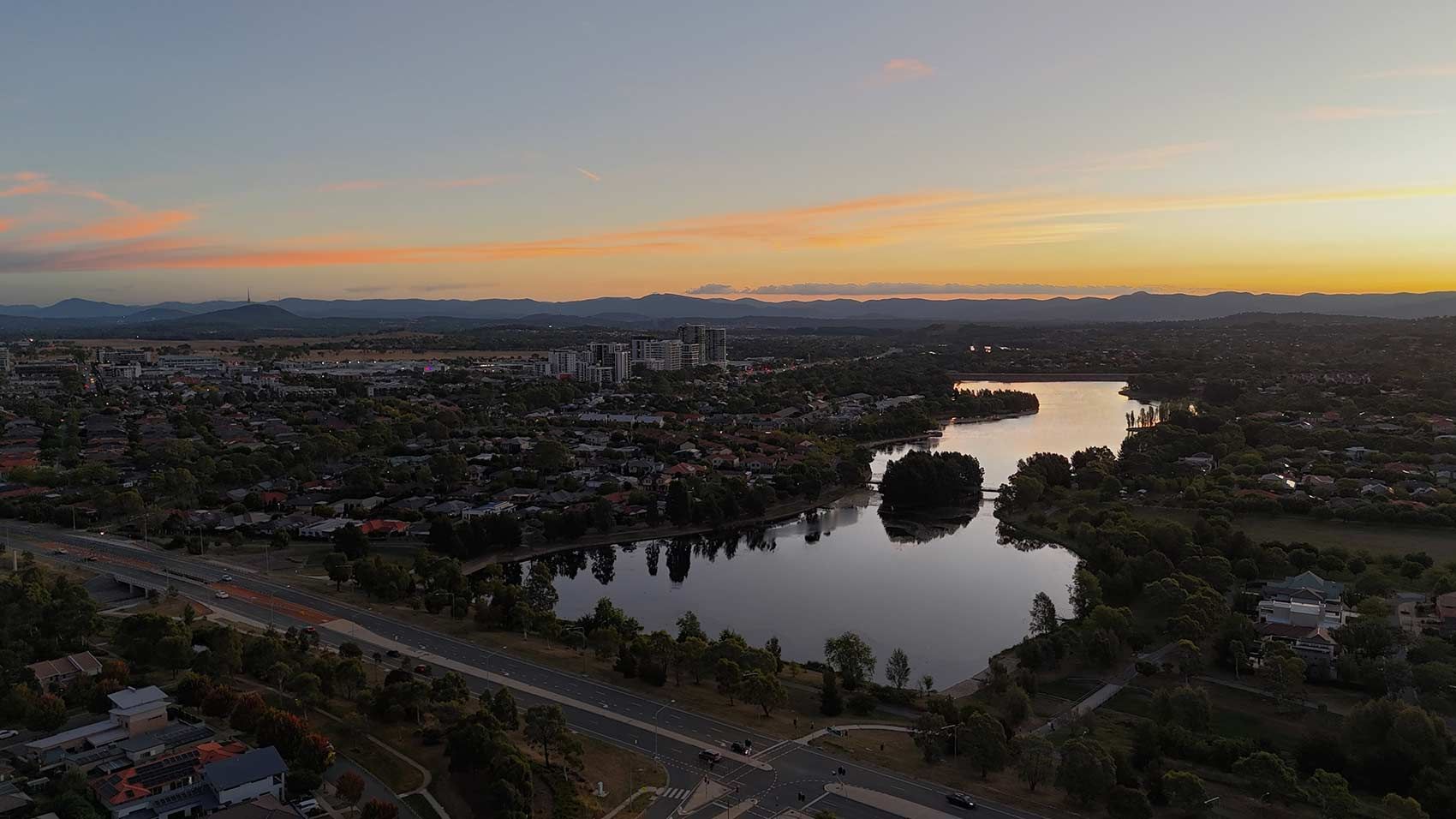 A View of Lake Reflecting the Sky at Dusk, Surrounded by a City With Houses and Buildings — CLF Landscapes in Gungahlin, ACT