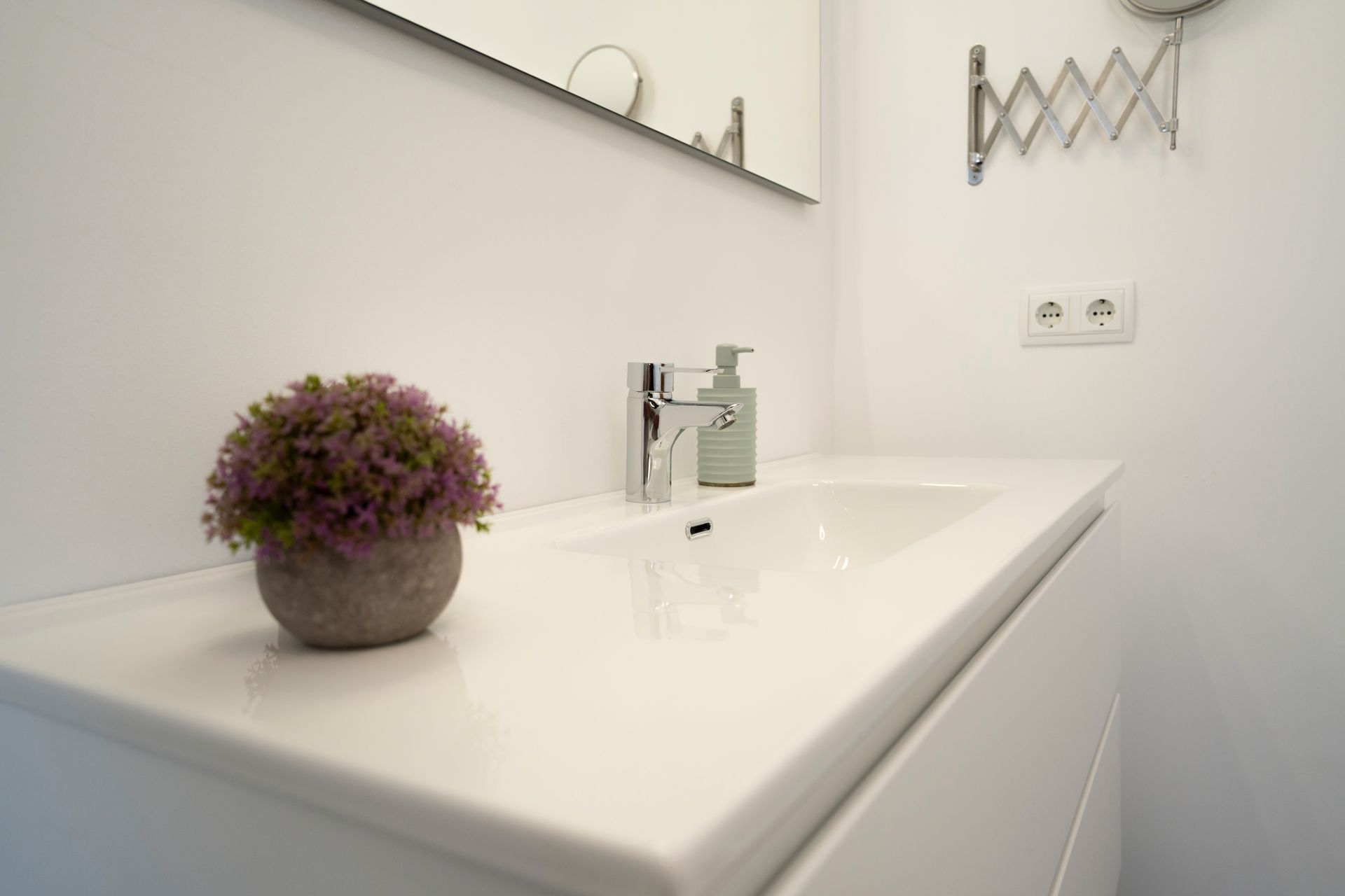 Lavabo de baño blanco con planta y grifo cromado.