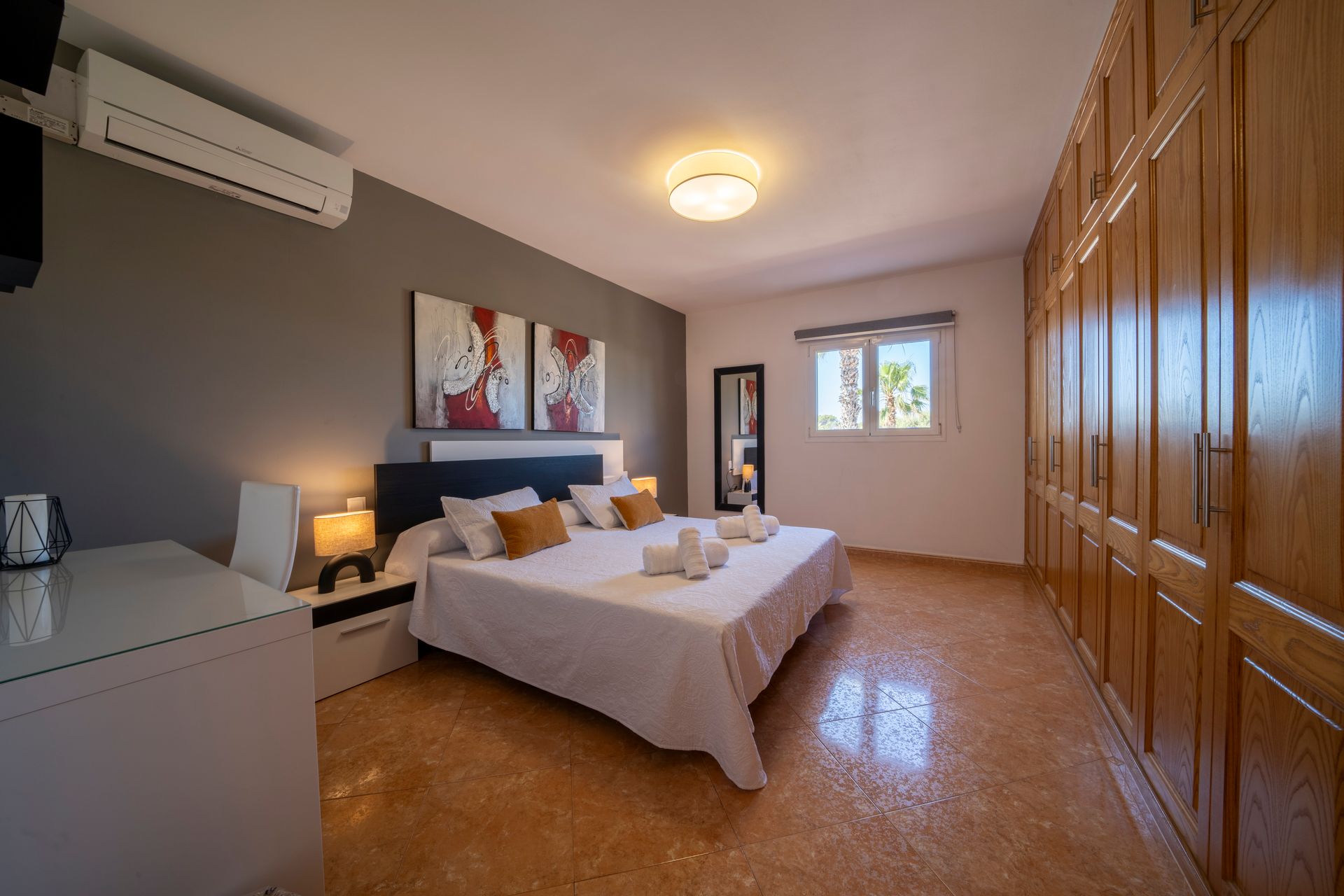 Dormitorio con cama, obra de arte, armario empotrado, cómoda blanca y ventana.