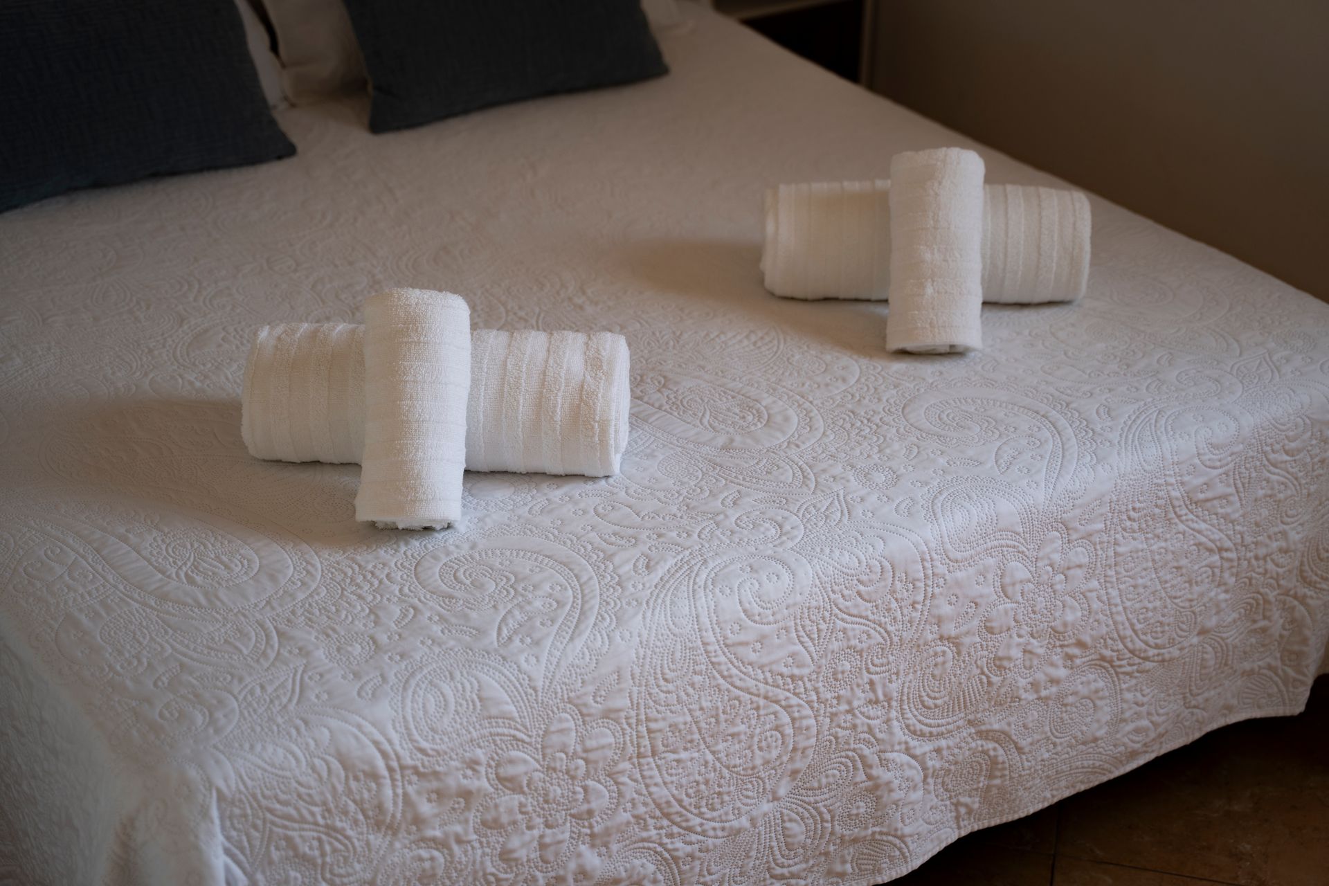 Toallas blancas dispuestas sobre una colcha blanca en un dormitorio.