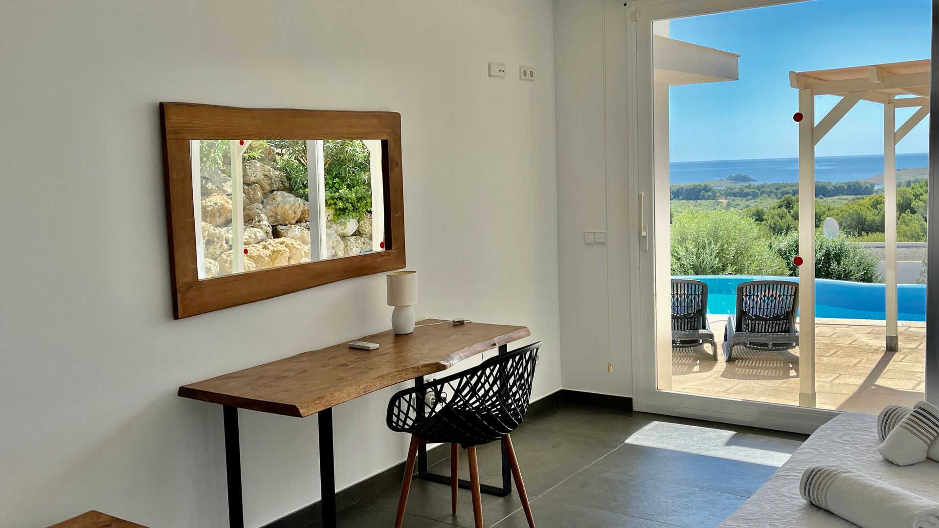 Escritorio con espejo, con vista a la piscina y al paisaje a través de una puerta abierta.