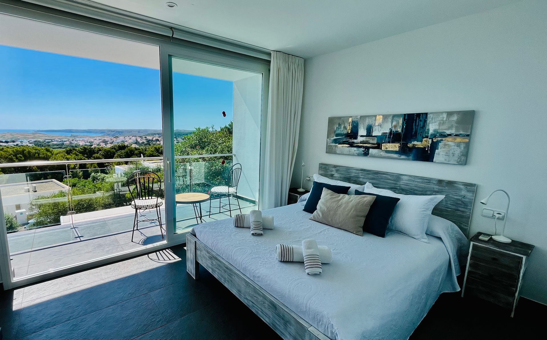 Dormitorio con cama king, balcón con vista a la ciudad, pintura en pared.