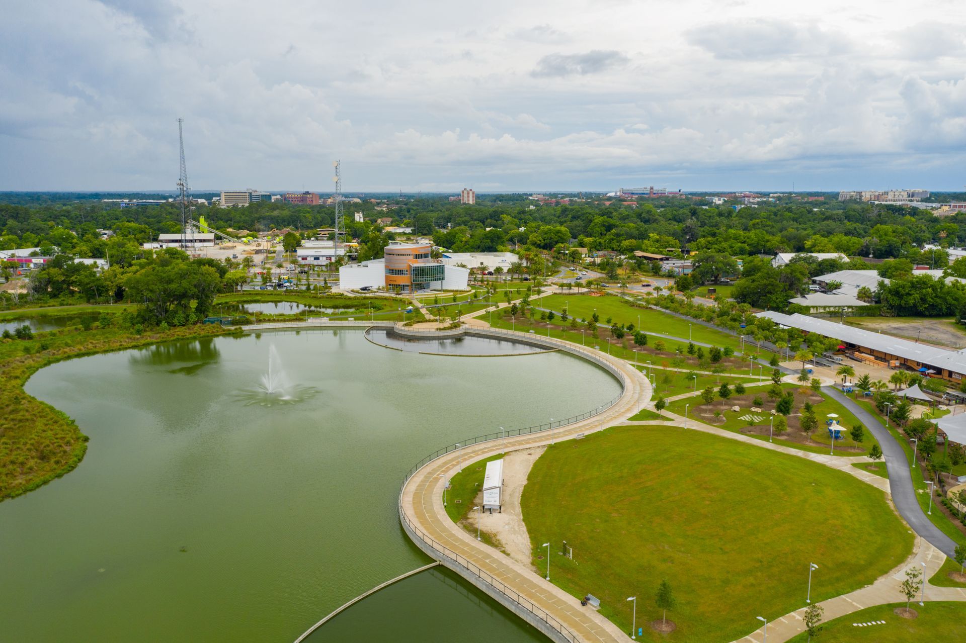 An aerial view of a park with a lake and a fountain.