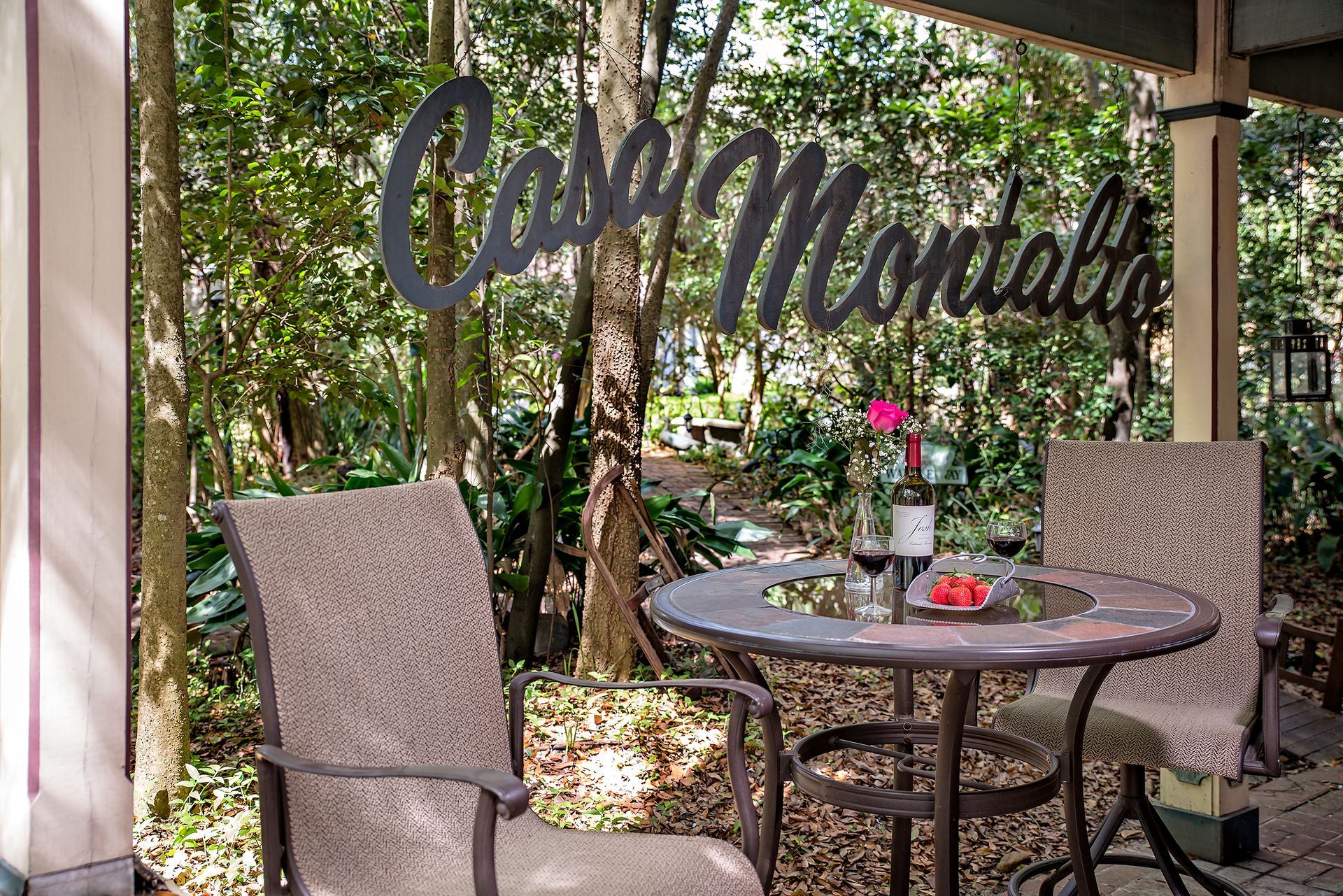 a table and chairs on a porch with trees in the background .