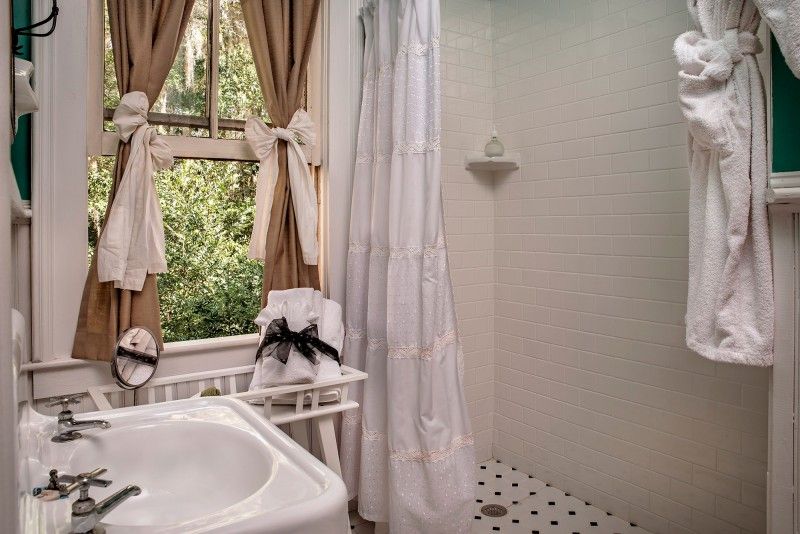 a bathroom with a sink , shower curtain , mirror and window .