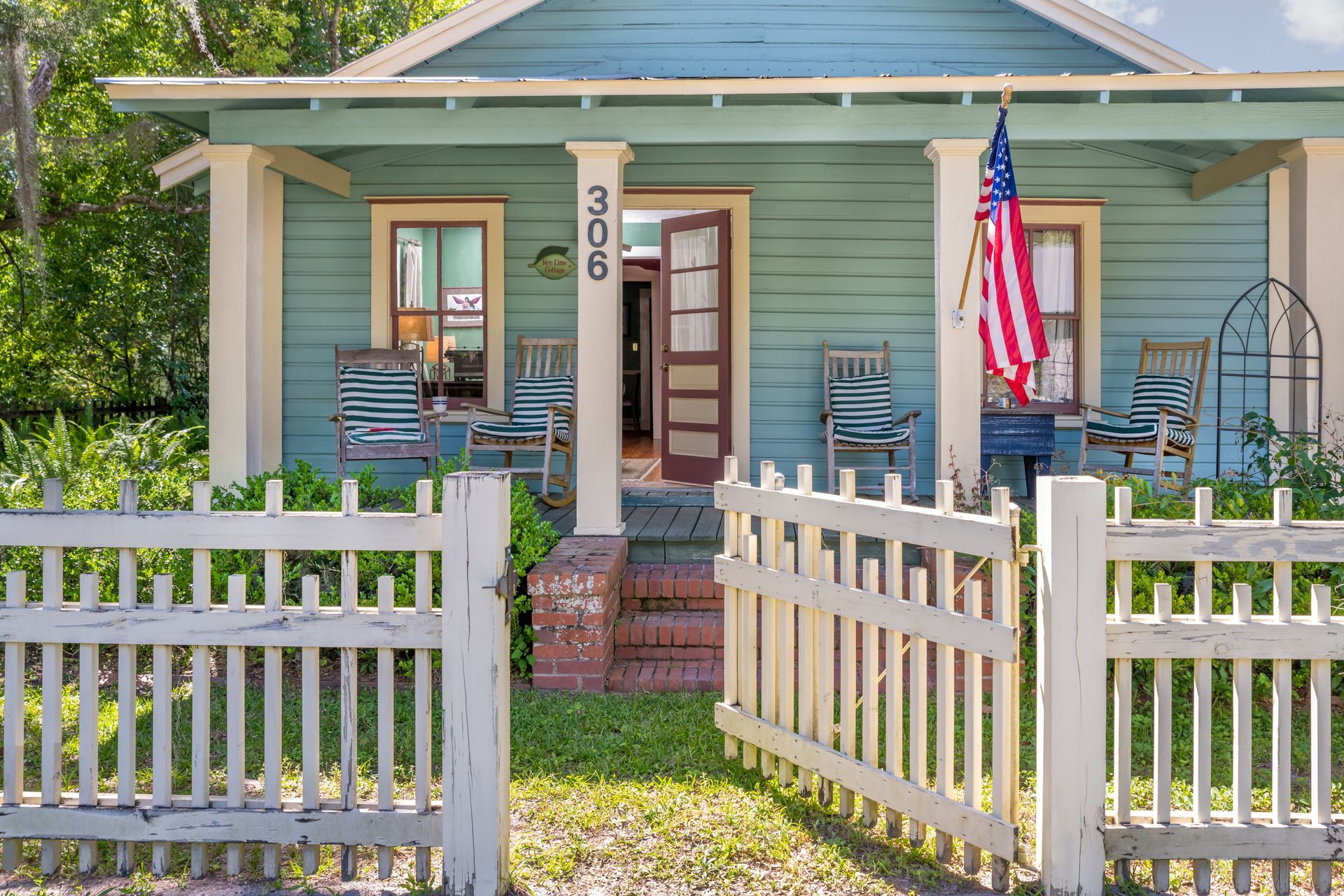 a small blue cottage with a porch and rocking chairs