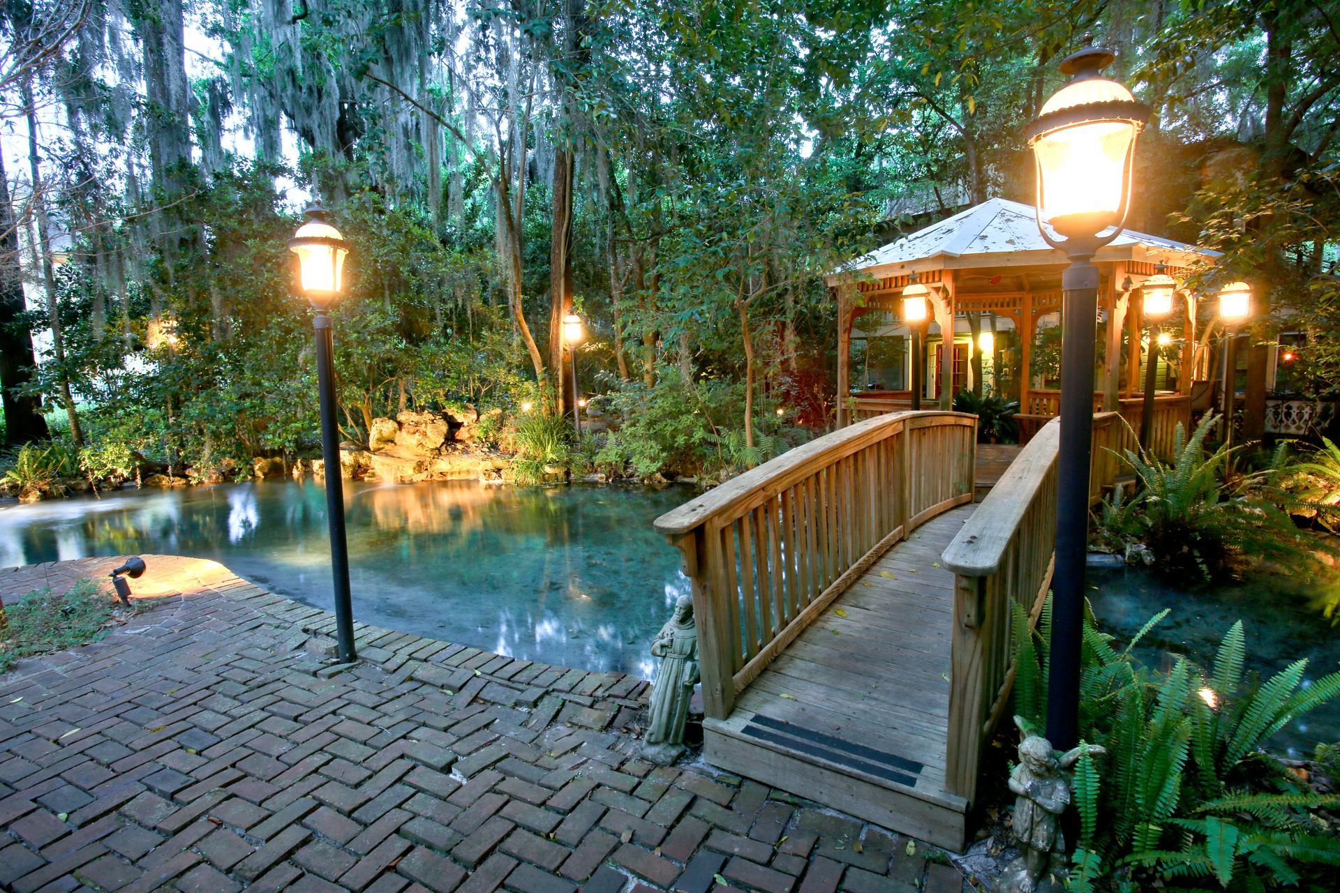 a wooden bridge over a pond with a gazebo in the background