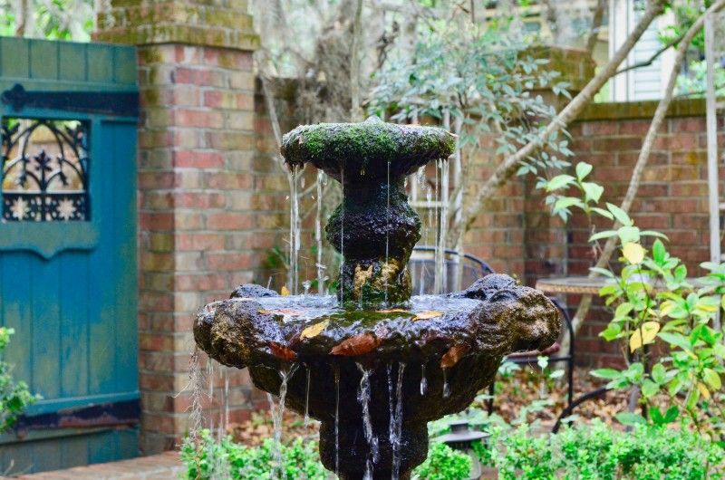 a fountain in a garden with a blue gate in the background .