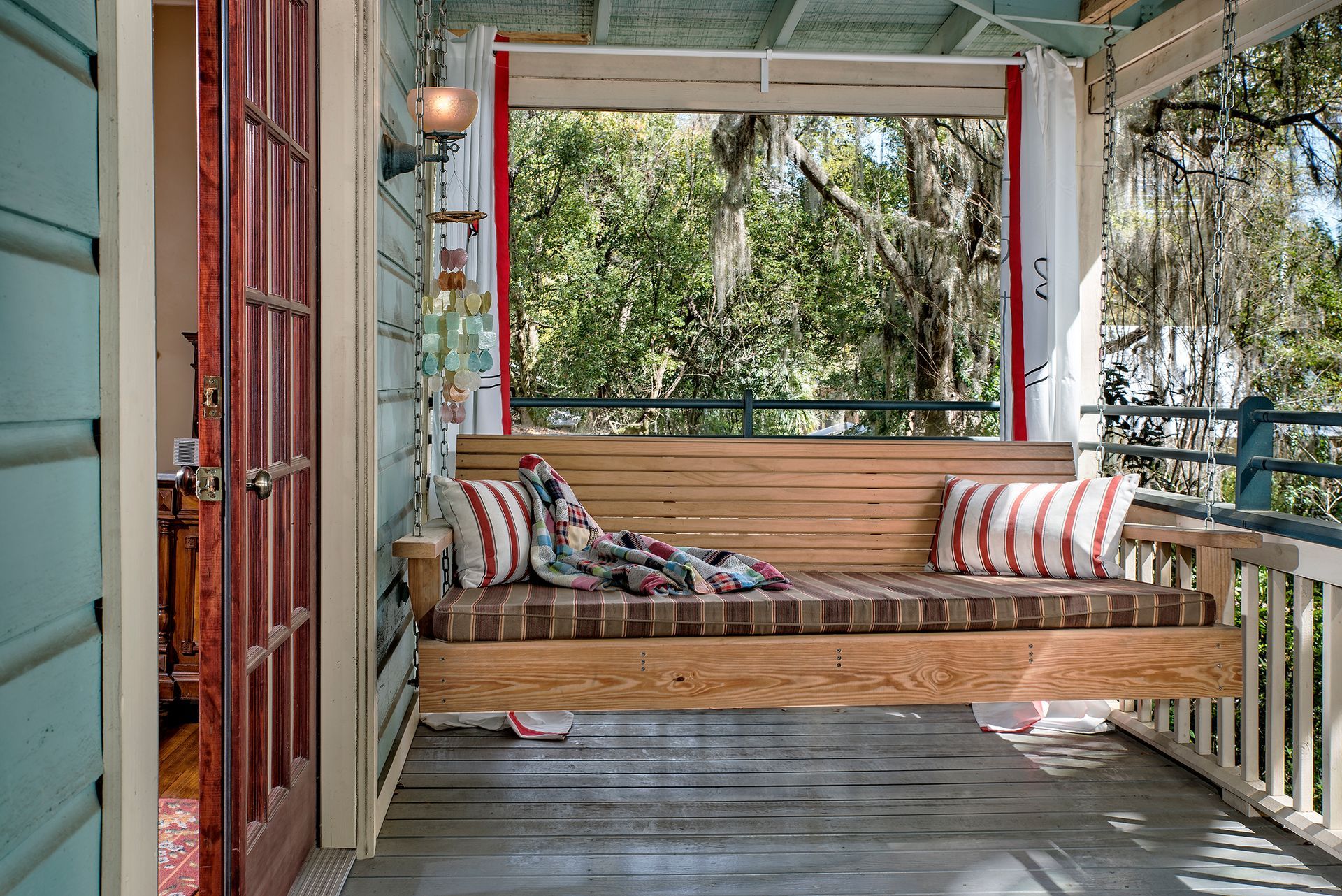 a porch with a wooden swing and pillows on it