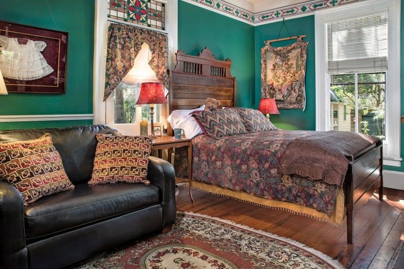 a bedroom with green walls , a bed , a couch , and a rug .