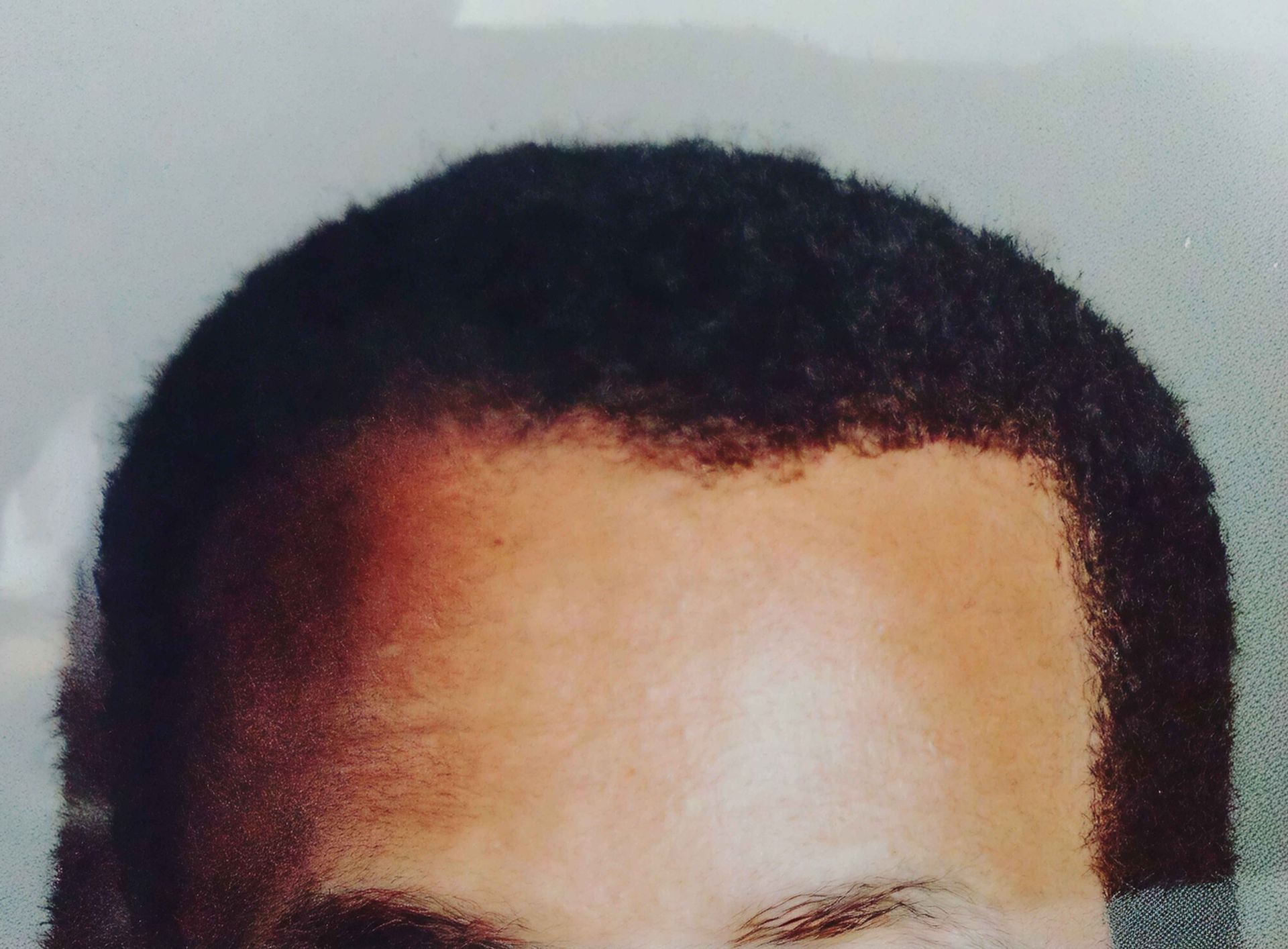 A man with gray hair is standing in front of a wooden dresser.