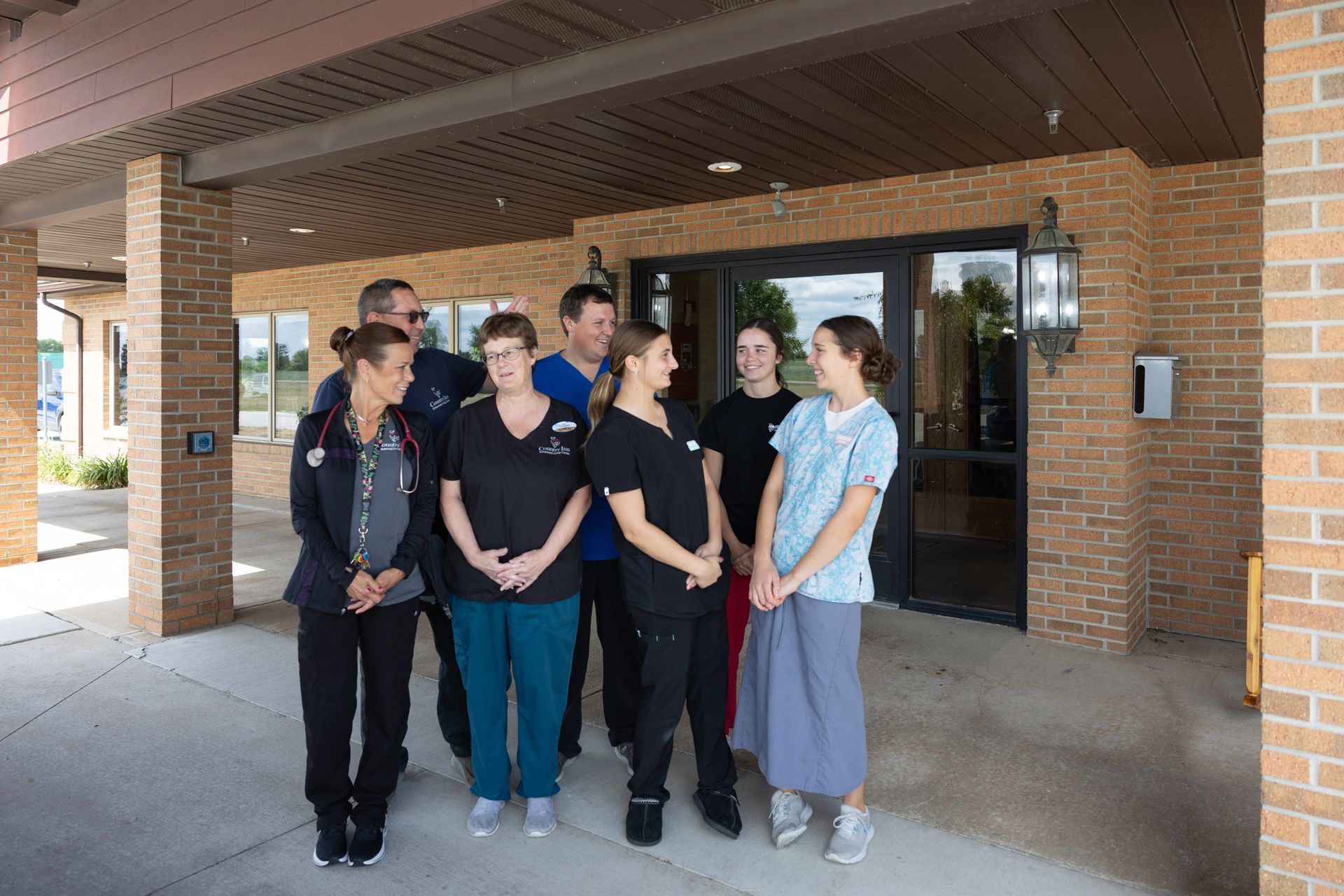 Medical professionals standing outside a brick building, smiling.