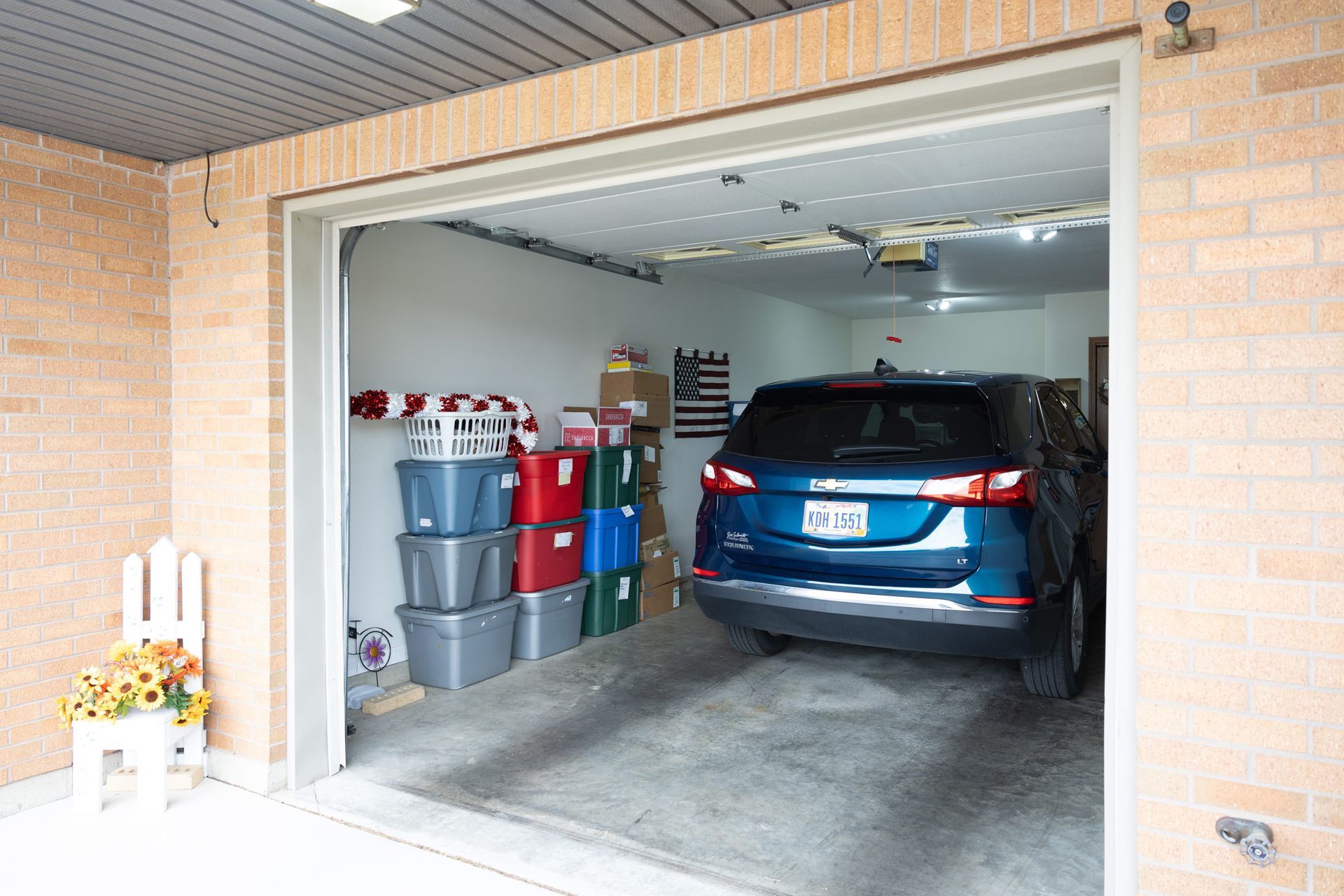 A blue SUV parked in a garage with storage containers on the left.
