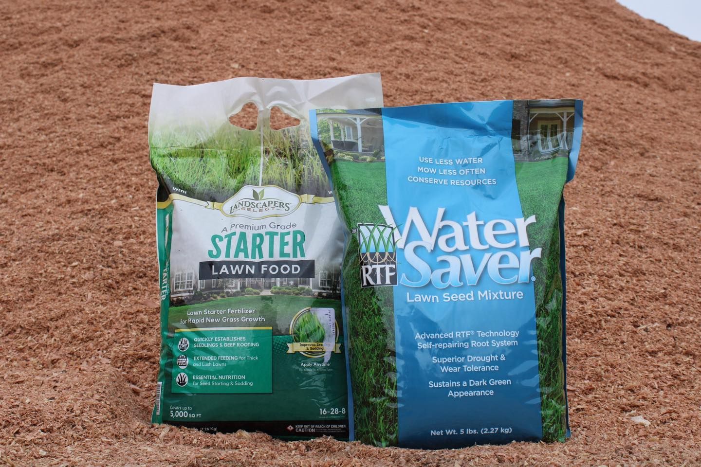 White garden sprinkler timer on a black slat wall, next to a shovel and rake.