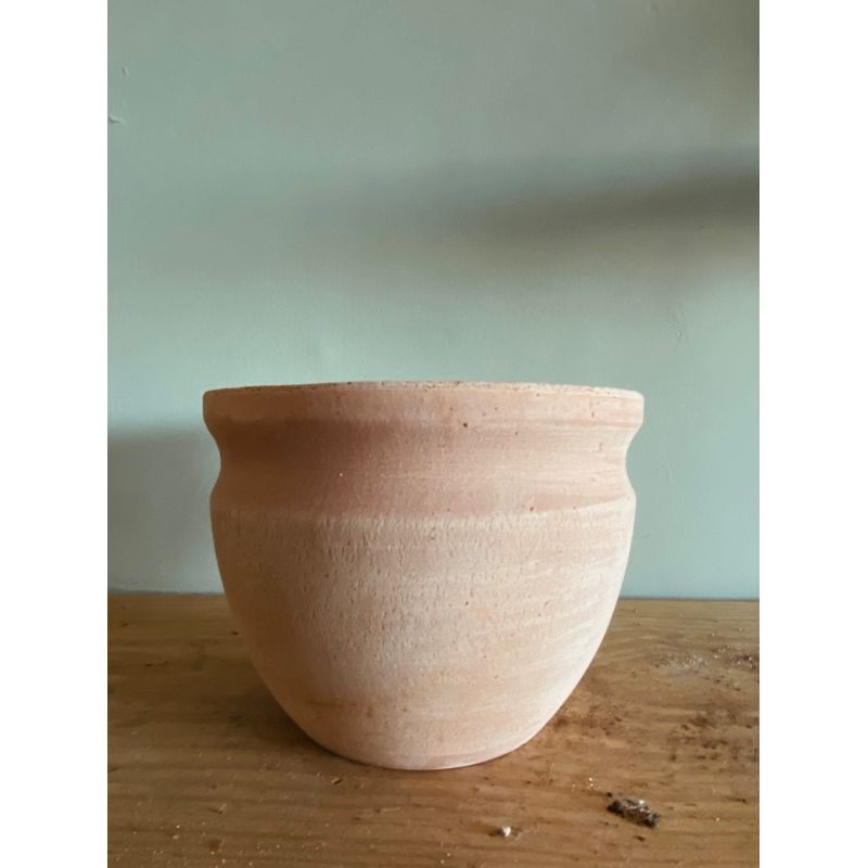 Terracotta flower pot with a rounded shape.
