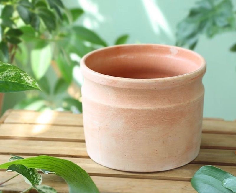 A small clay pot sits on a wooden table