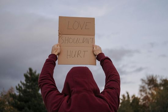 Person in maroon hoodie holds sign: 