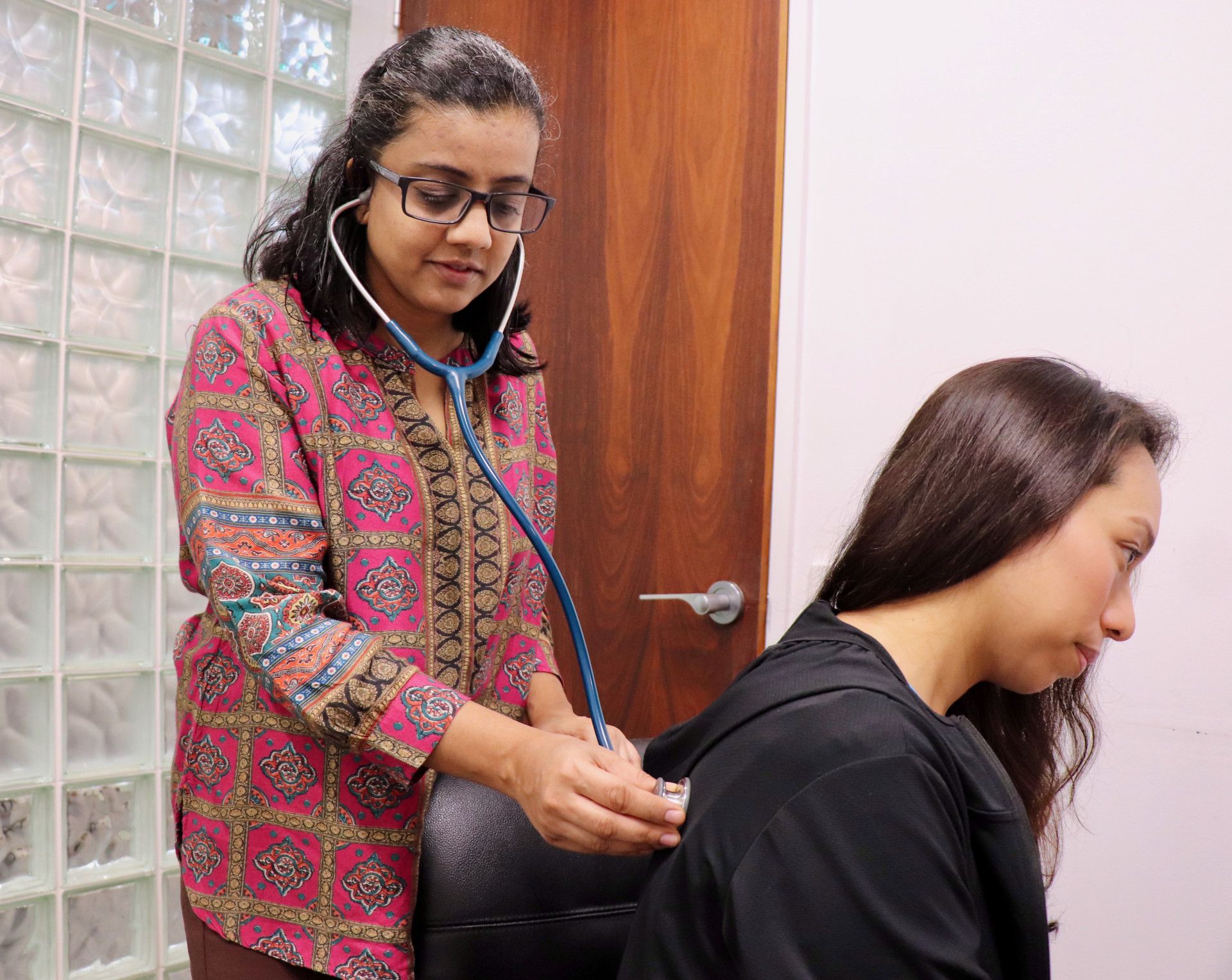 Doctor using a stethoscope to examine a patient's back in an office.— One Stop Medical in Mackay, QLD